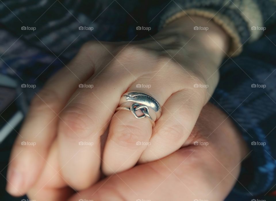 woman and man holding hands with silver rings on her finger one with a heart wedding rings love together for valentine's day