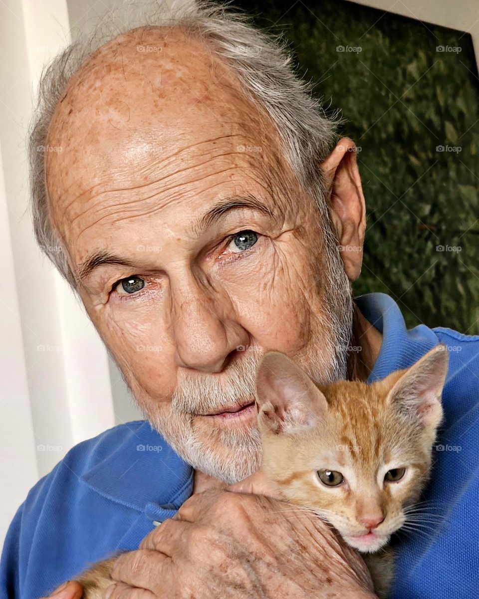 Portrait of a man with an orange tabby kitten. His expression is of happiness. He is in love with the new family member (Tango).