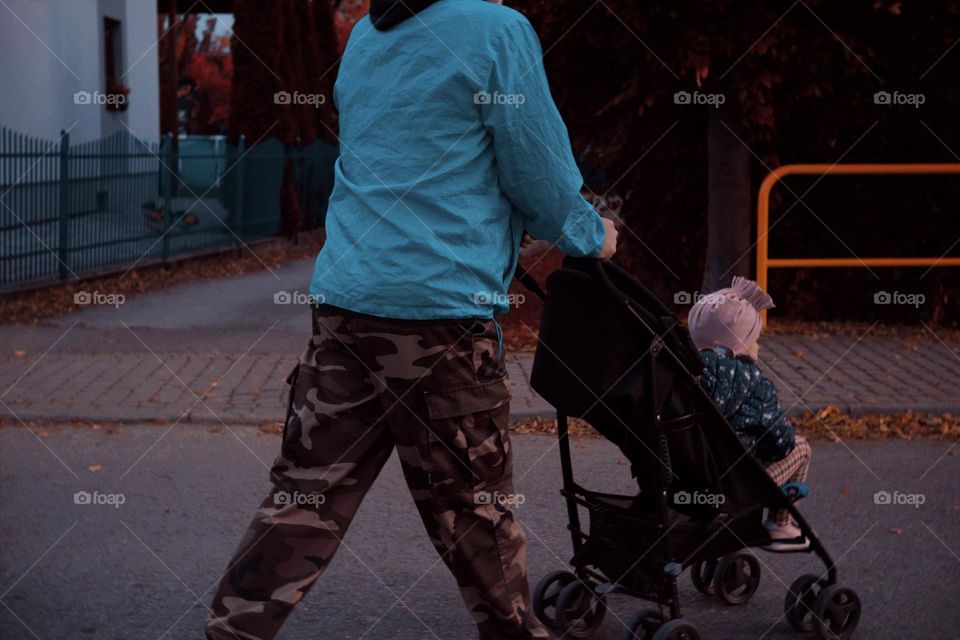 A man carries a child in a baby carriage