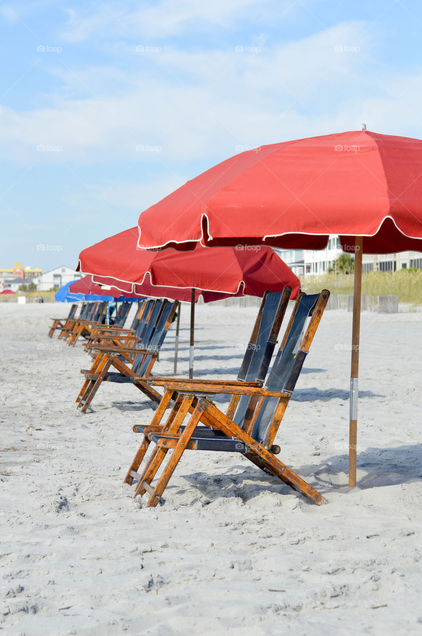 Row of lounge chairs and umbrellas set up on the beach with no people