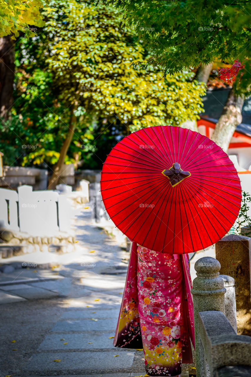Japanese girl in kimono carrying a red umbrella.
