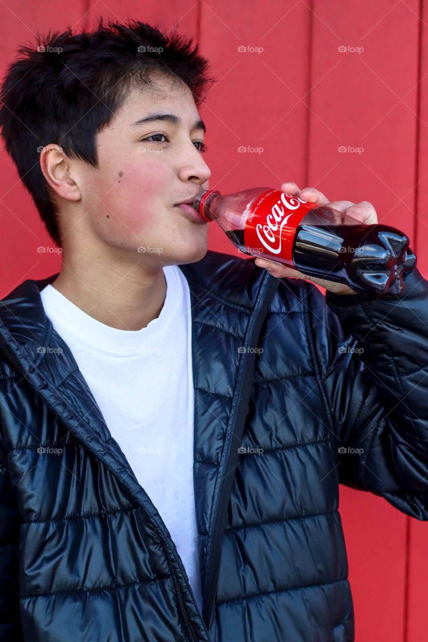 Young handsome man having a drink of Coca-Cola from a bottle