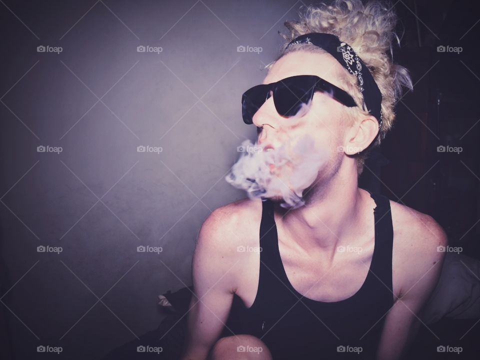 Young stylish boy in sunglasses smoking a cigarette