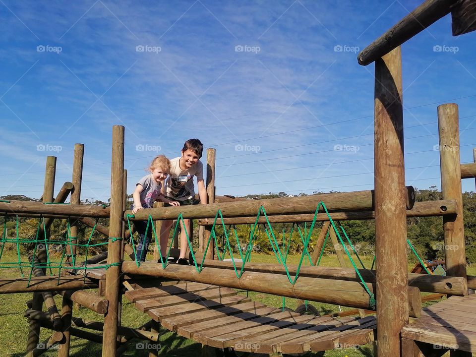 Kids playing on a wooden jungle gym