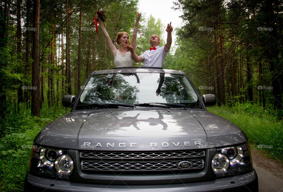 Bride and groom enjoying in car at forest