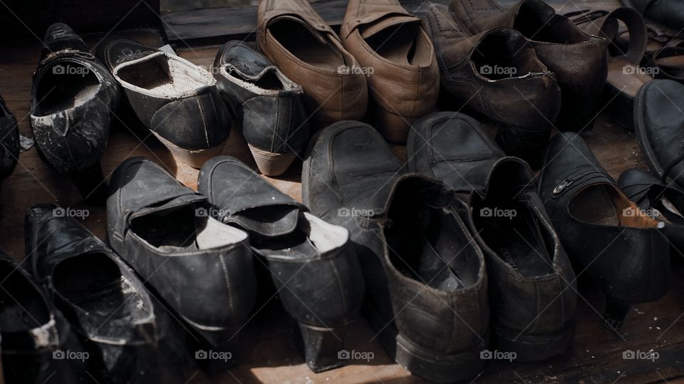 A pile of various kinds of used leather shoes on the table