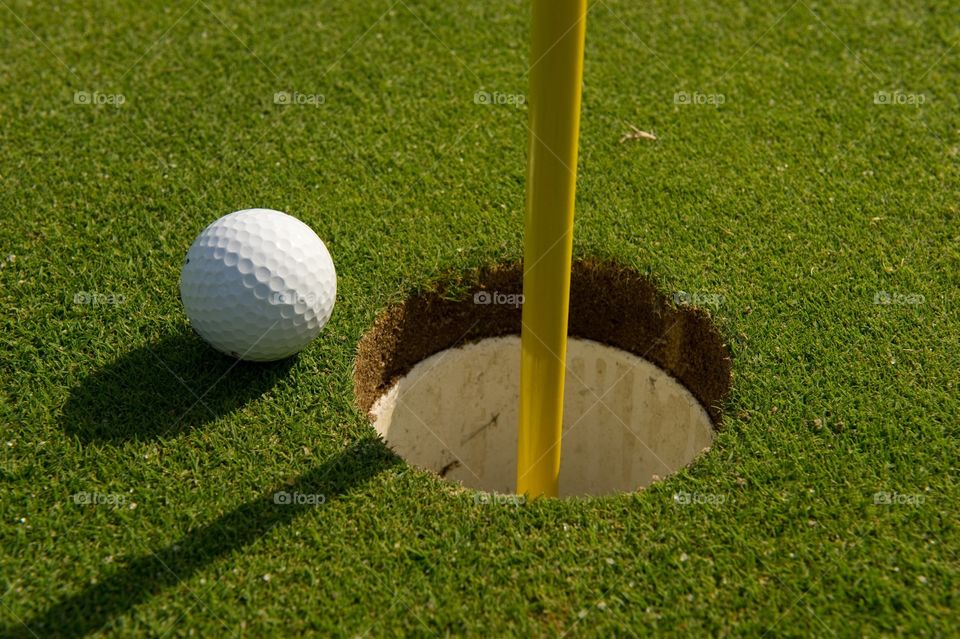 Golf ball by the cup on green