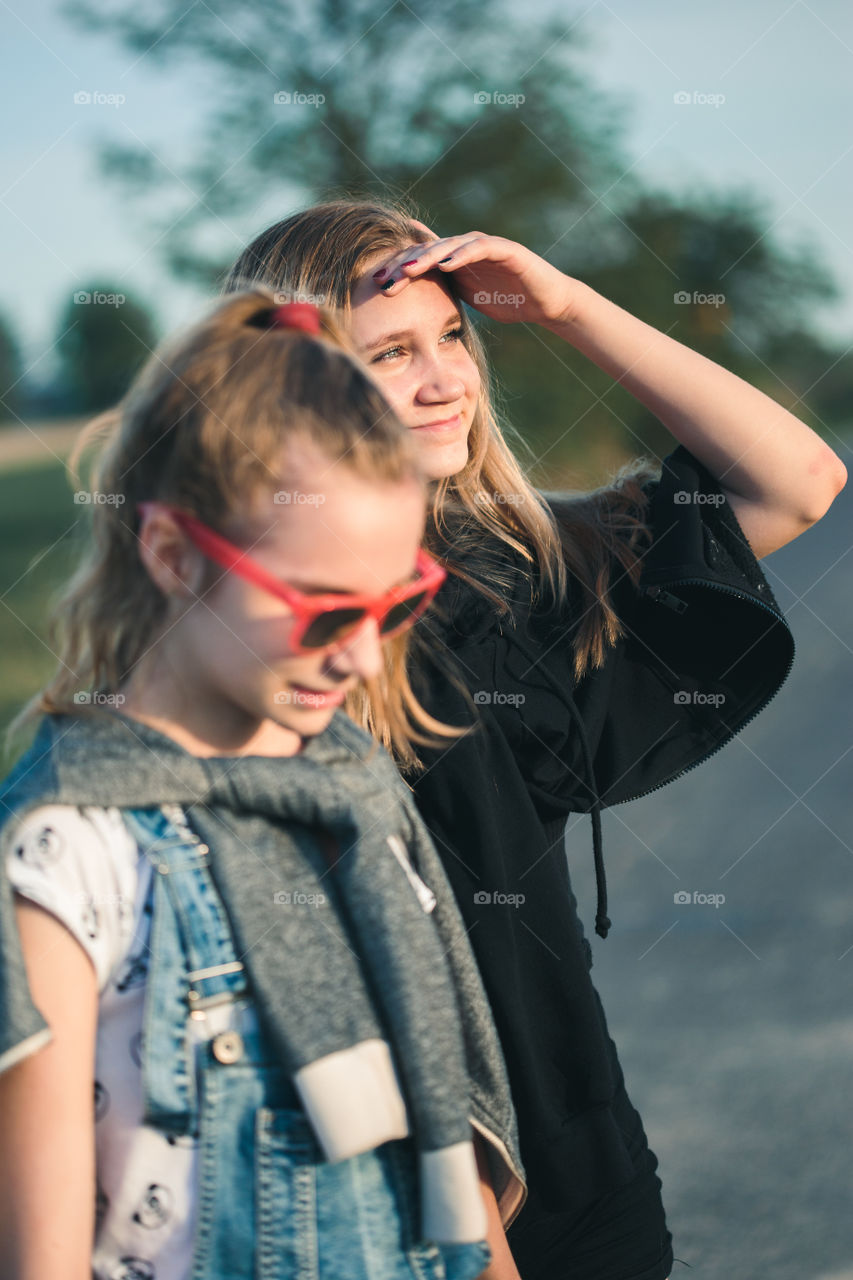 Teenage smiling happy girls having fun walking outdoors, hanging, spending time together on summer day. Real people, authentic situations