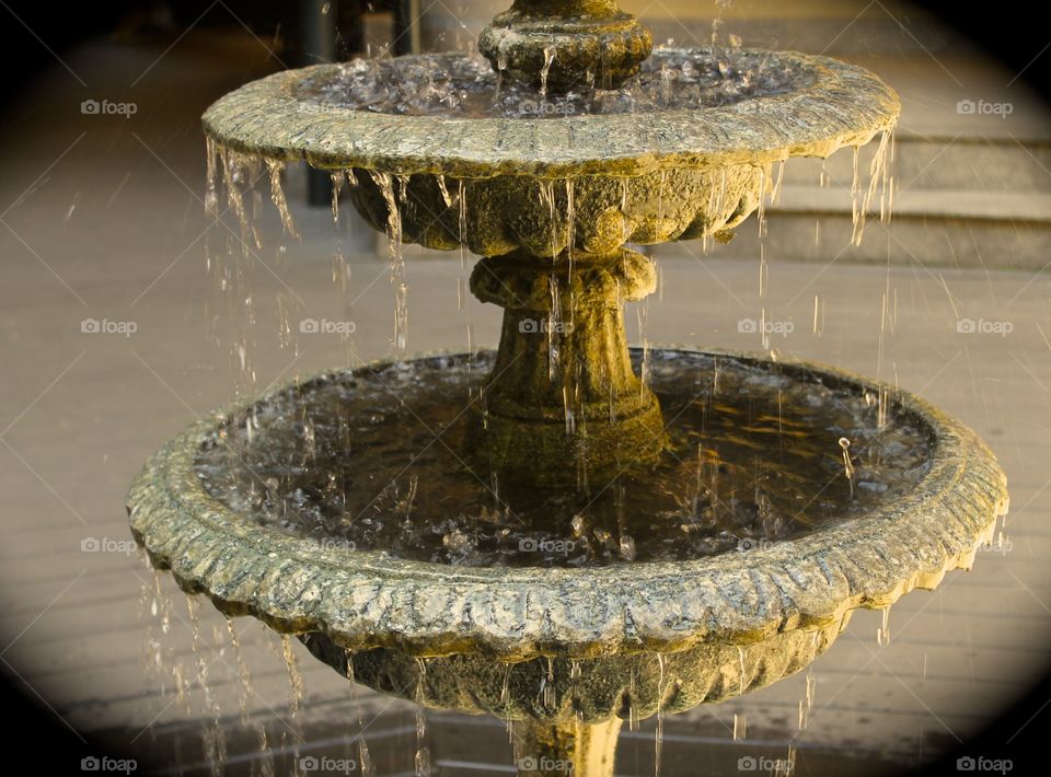 Round, outdoor fountain with water dripping off of it