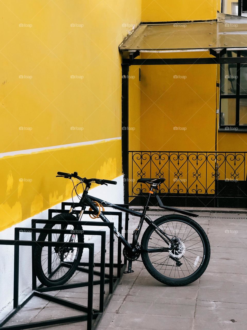 One lonely bicycle near yellow wall in sunny summer day, no people 