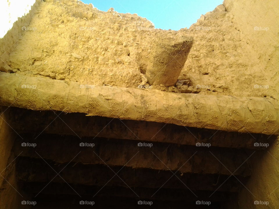 The roof of an old house is built of mud and palm trunks