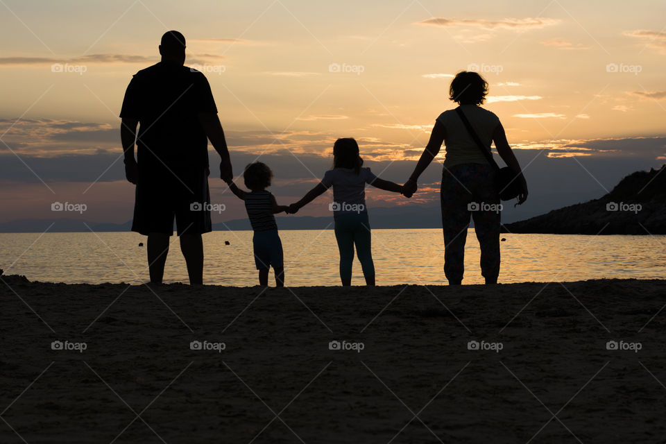 family on beach at sunset. young family on beach at sunset,silhouettes effect
