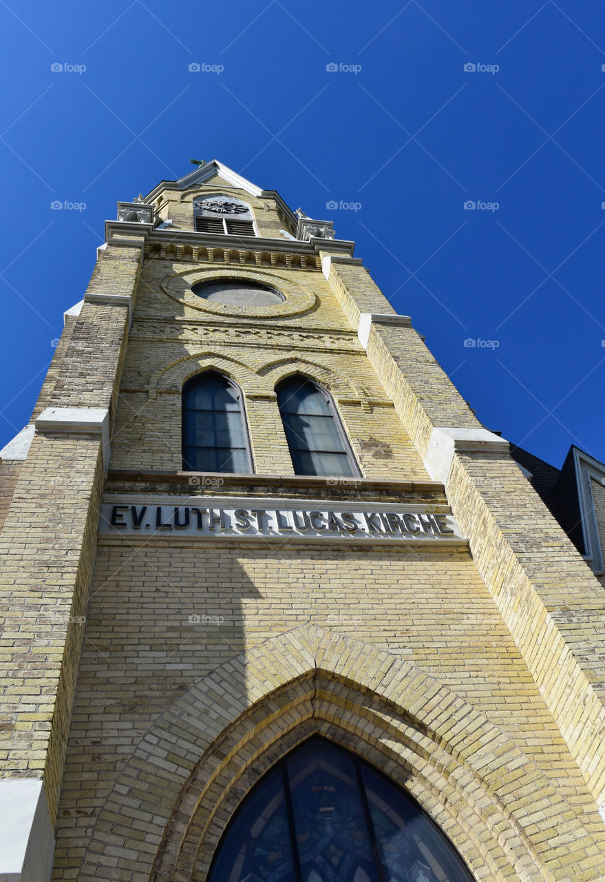 Cream city brick church spire against a blue sky