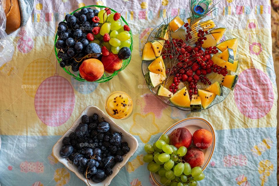 Four fruit salads, summer fruits: peaches, green and dark grapes, black and red currants, watermelon, plums, melons