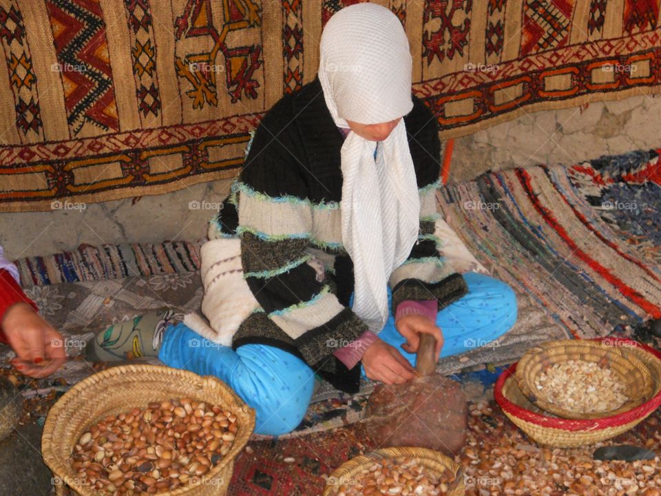 Woman sitting on colorful rugs working with nuts in Morocco 
