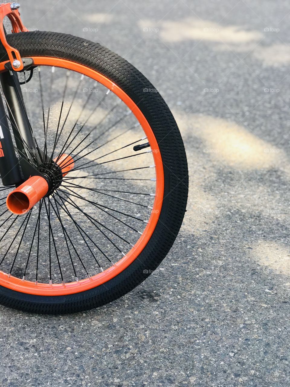 The orange and black wheels of bicycle, the toy for the summer rides.
