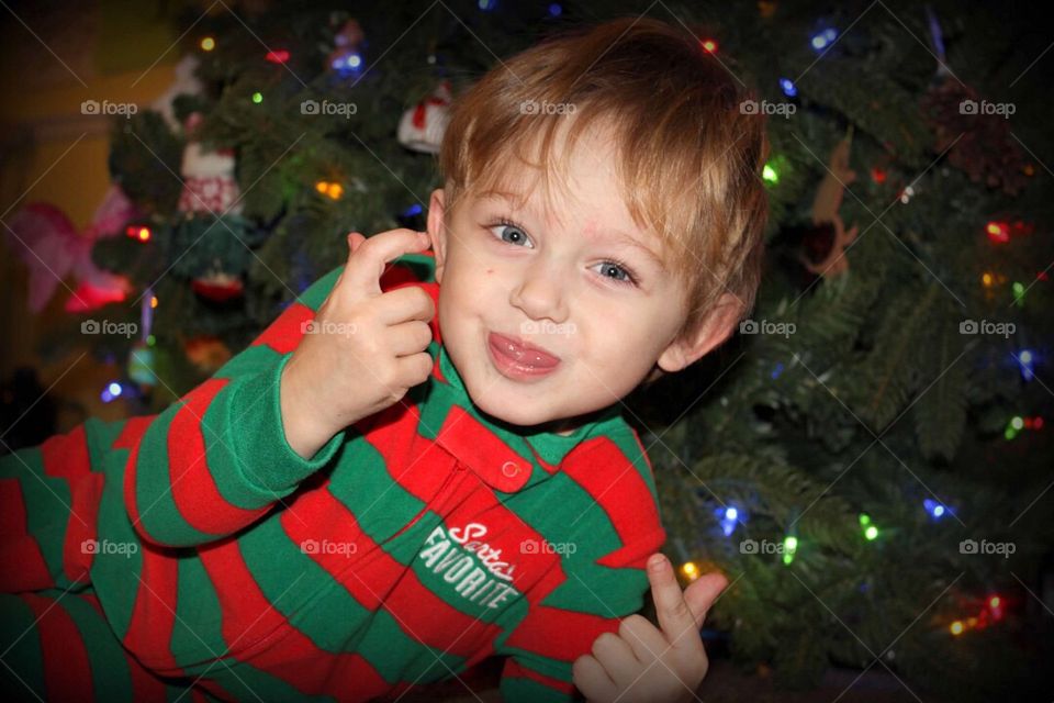 Boy sitting in front of illuminated christmas tree