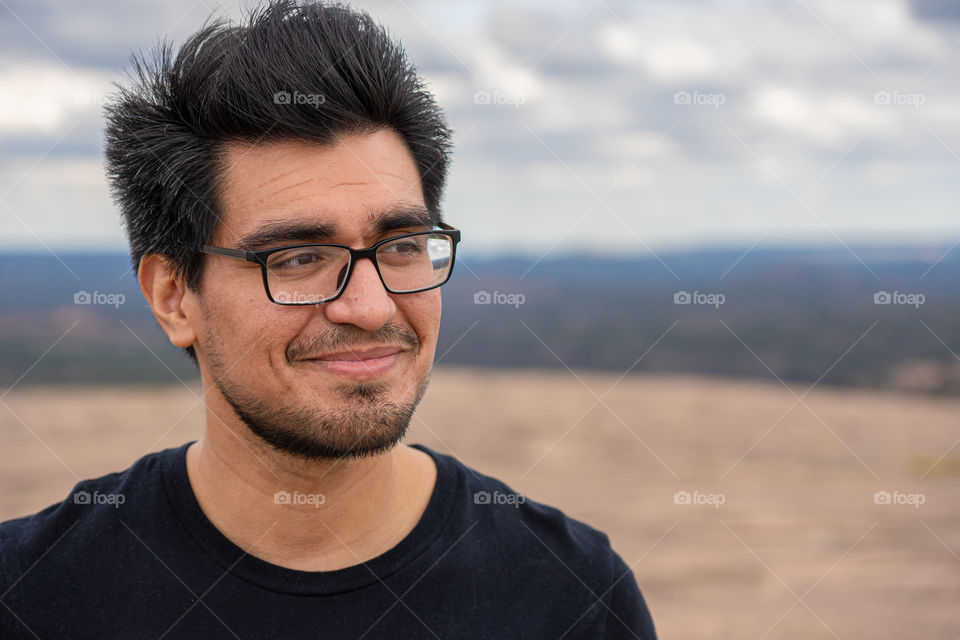 man smiling looking off into the distance on top of the hill after a long hike