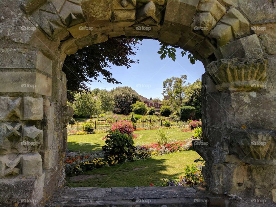 An ancient stone archway though to a beautiful garden.