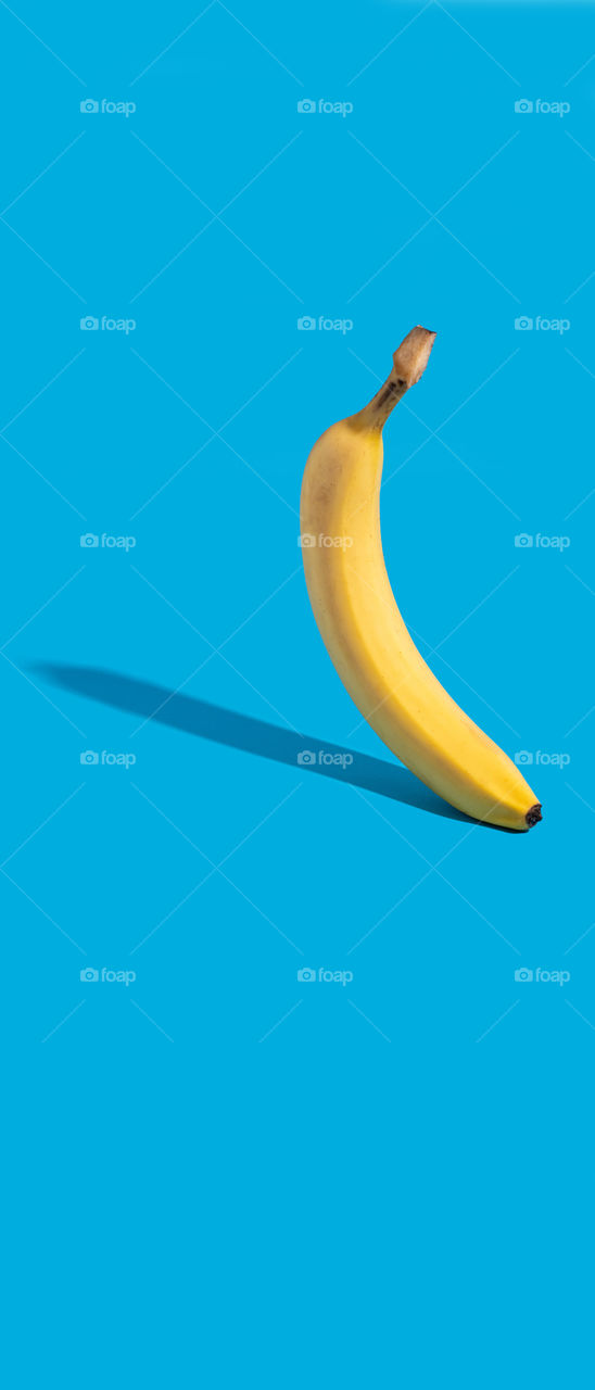 Banana on a blue background. Phone wallpaper. 21:9