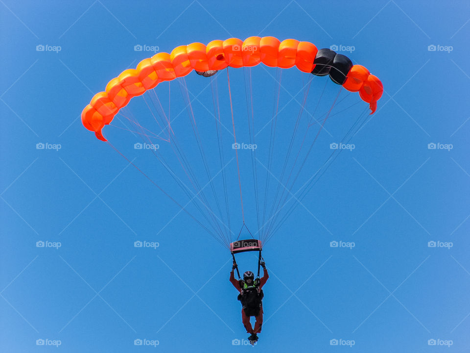 Clash of colours: A search & rescue parachutist practices jumps and precision landings. His bright orange suit & parachute contrast against the bright blue, cloudless sky.