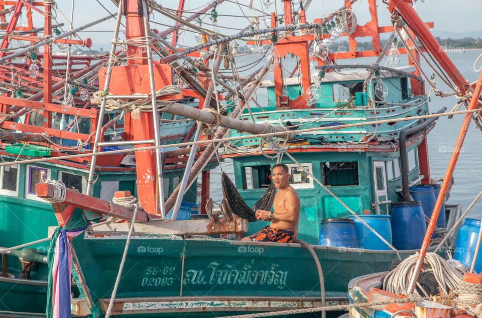 a Thai Fisherman at his fishing boat at a Pier in Naklua District Chonburi Thailand Southeast Asia
