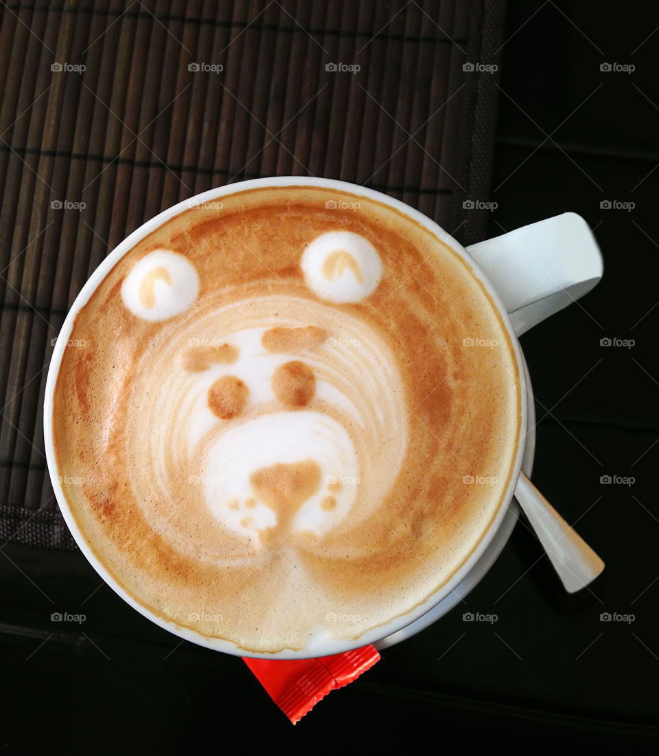 Overheard view of Latte art  — drawn bear in a cup of coffee with cream 