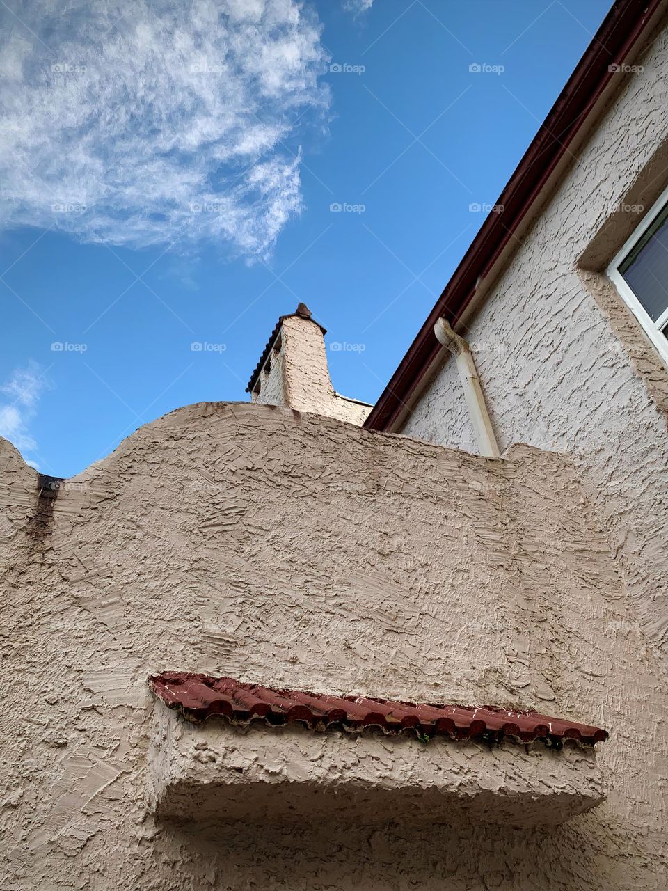 White and red spanish old style architecture residential large house built in the early 1900s. Side windows and top walls with aging signs before sunset with sunlight on the tip of the roof.