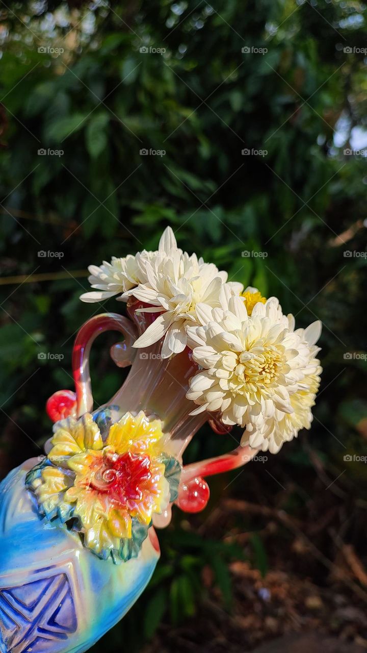 Beautiful white flowers in a colourful flowerpot with a flower sculpture