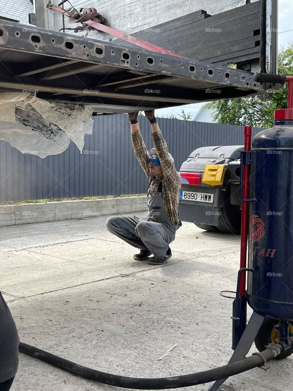 Photo of a random moment of a worker repairing a car wearing very funny glasses