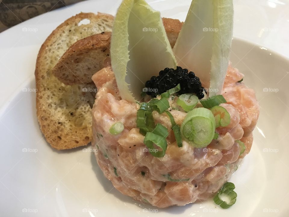 Salmon tartare and classic french cocktail sauce with mayonnaise and brandy garnished with endive and toasted french bread 