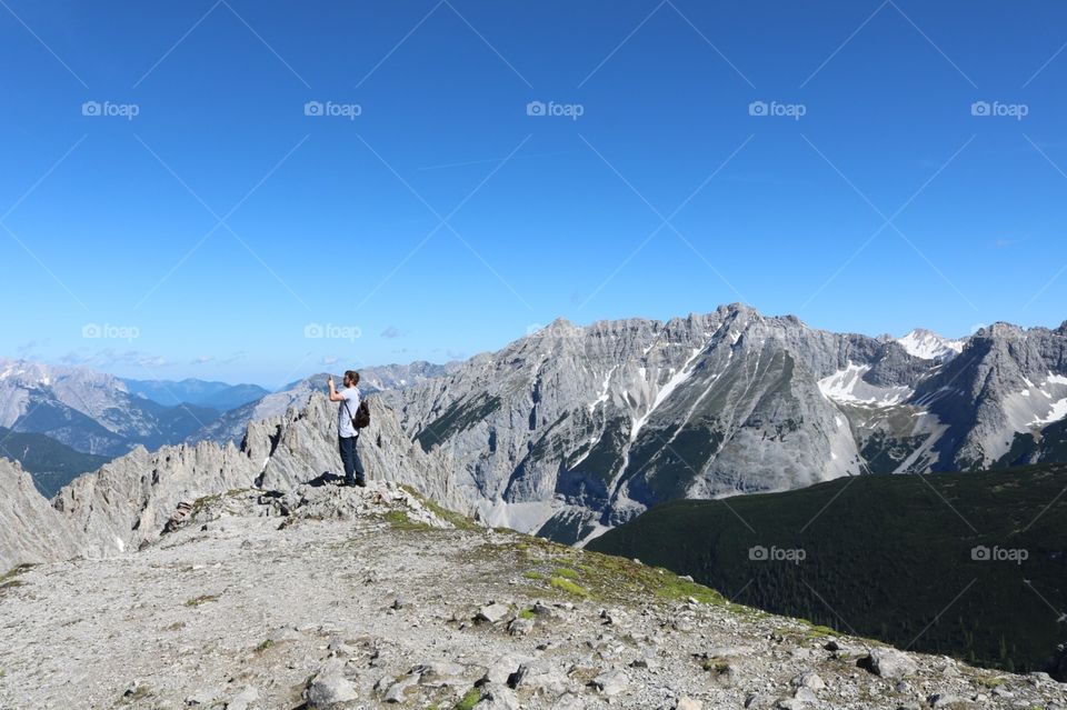 Homem fazendo uma foto nos Alpes austríacos com lindo céu azul