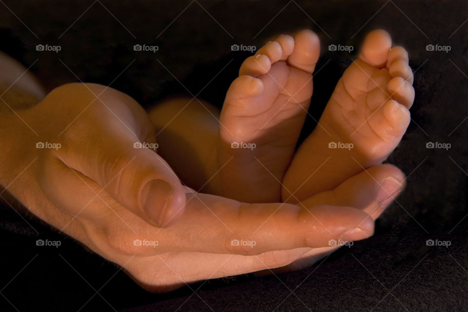 Baby’s feet being held tenderly in father’s hands