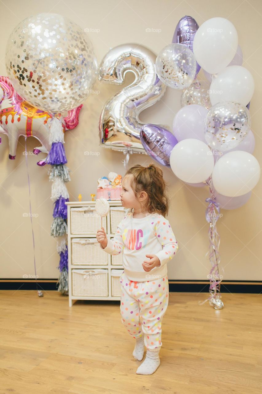 Small birthday girl in polka dot pajamas hold candy