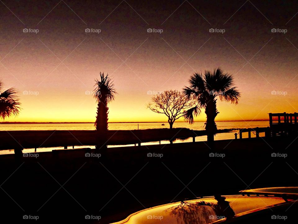 The sunset was a perfect conclusion of the day. It was silky, smooth collusion of sky burst of yellows, various hues, orange, tangerine and metallic gold. Palm trees were silhouetted 