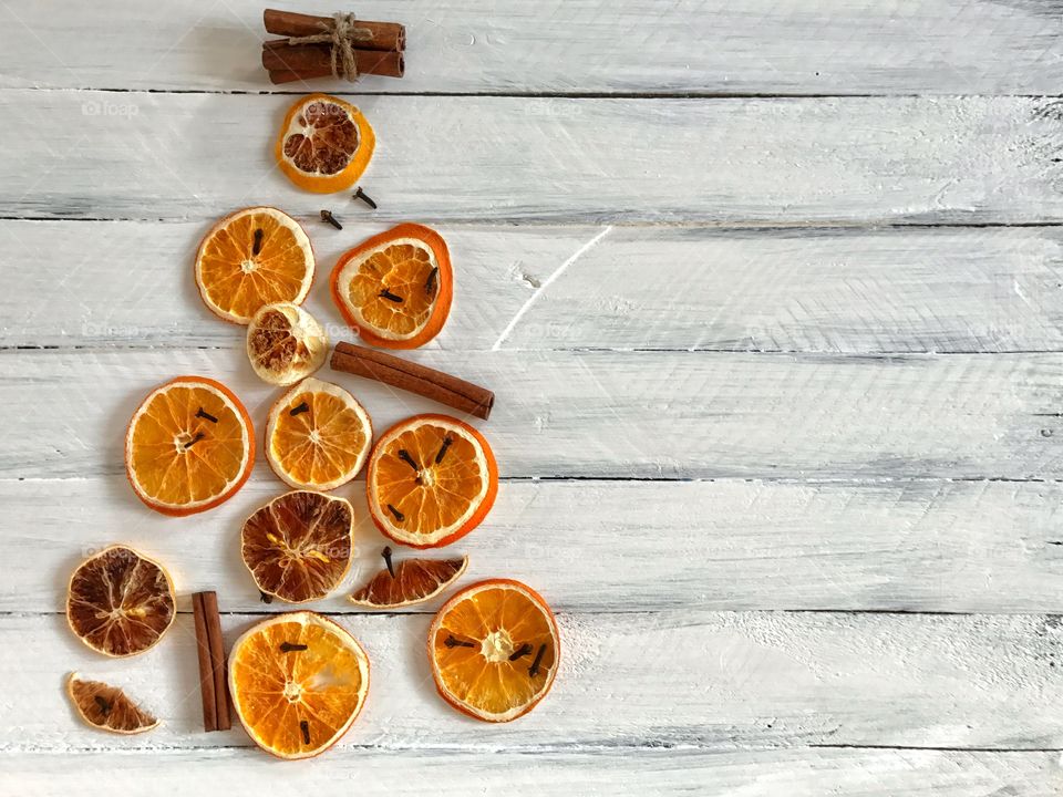 Dried slices of orange and lemon with cinnamon sticks on a white wooden surface