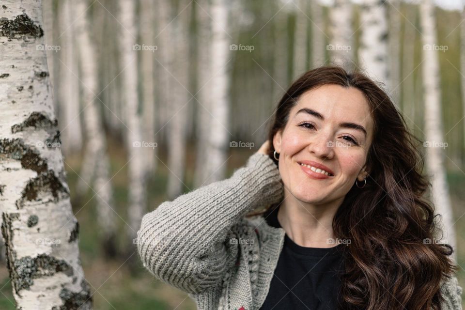 Young woman, being happy and smiling, while on a walk in nature, during a beautiful spring day.