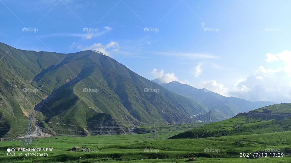 A beatiful picture of Lush green Meadows & moutsins near Pir ki Galli Mughal road on shopian side in Summer having clear Blue sky & Clouds....
