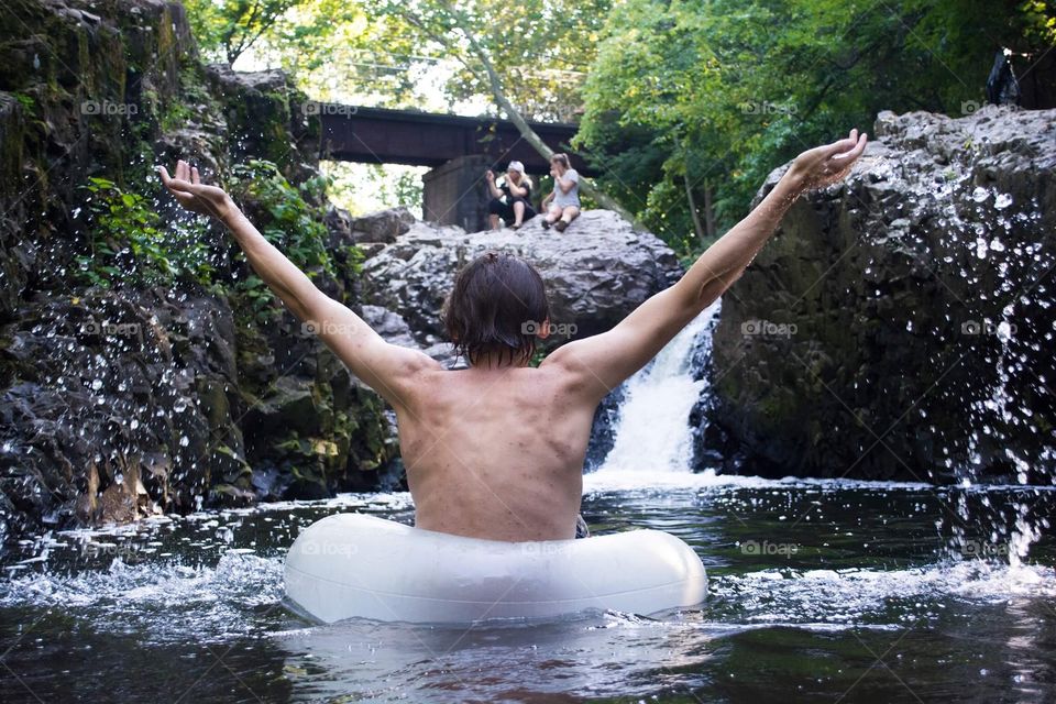 Guy has fun at waterfall in summer 