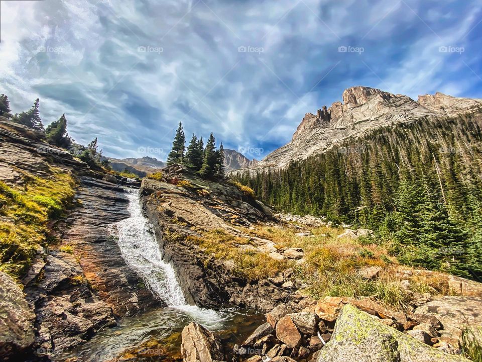 Water cascades down rocks with a mountain looming in the background 