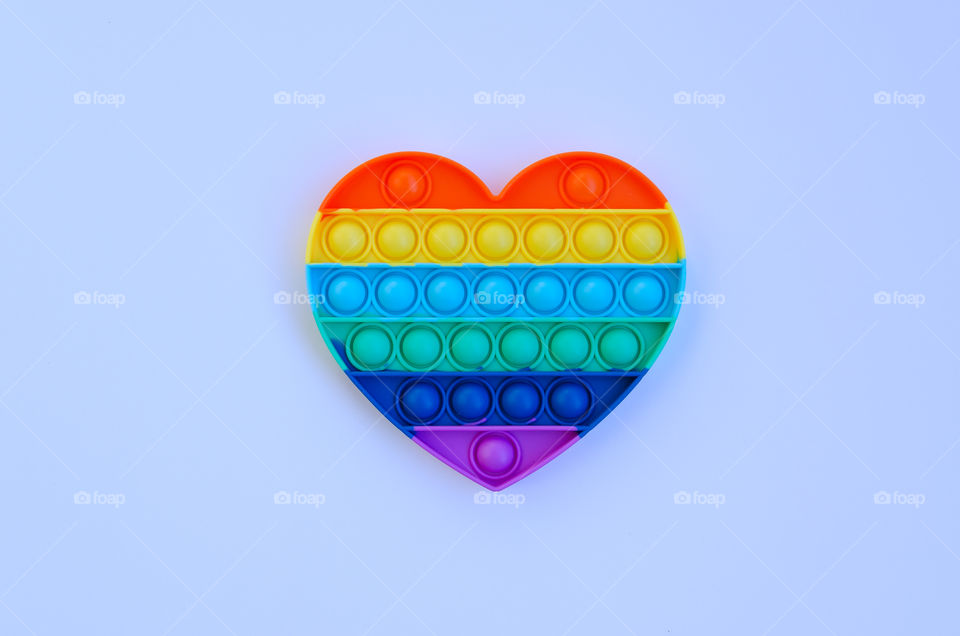 Top view of anti stress sensory toy Pop it rainbow heart on white background. Popular, trend toys in 2021
