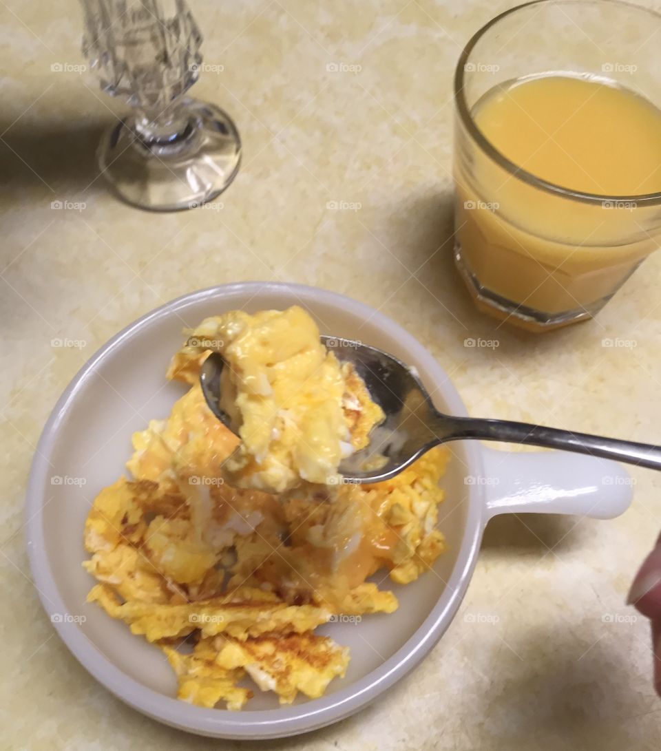 Morning ritual eating scrambled eggs with orange juice
