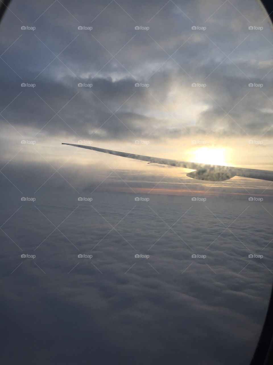 Airplane wing, sun and clouds from the illuminator 